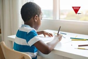 Child drawing by a sunlit window, symbolising hope, safety, and emotional support.